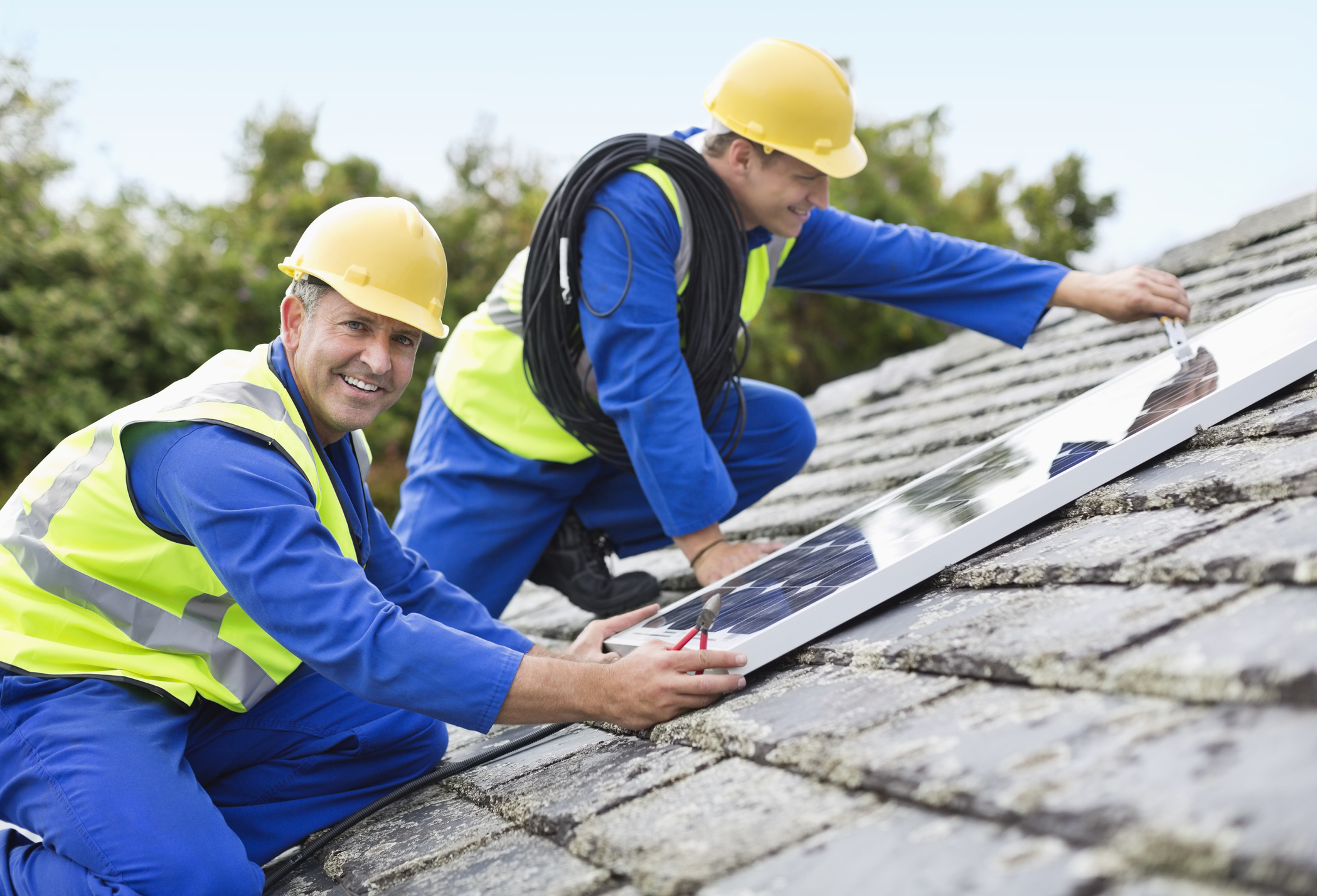 solar company technicians installing solar panels on roof