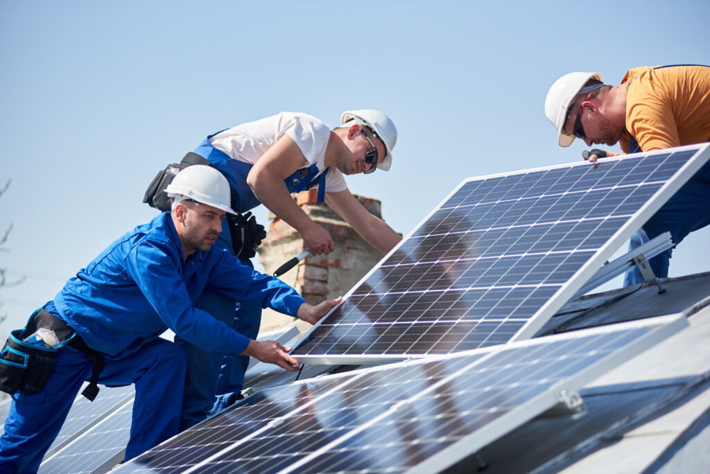 three residential solar technicians installing solar panel on roof