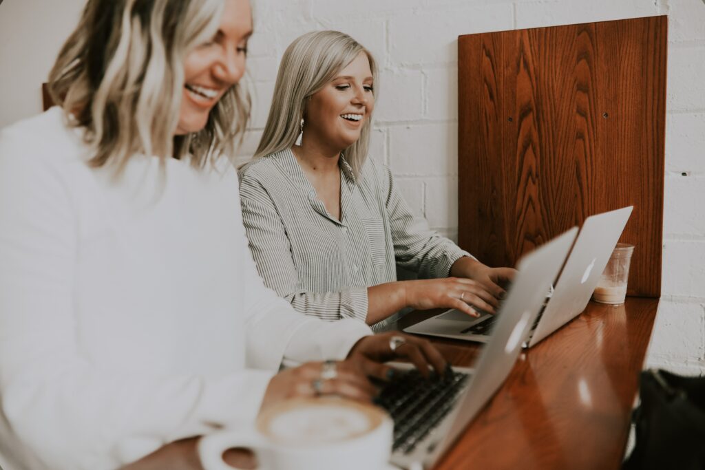 two women happy employees smiling computer working