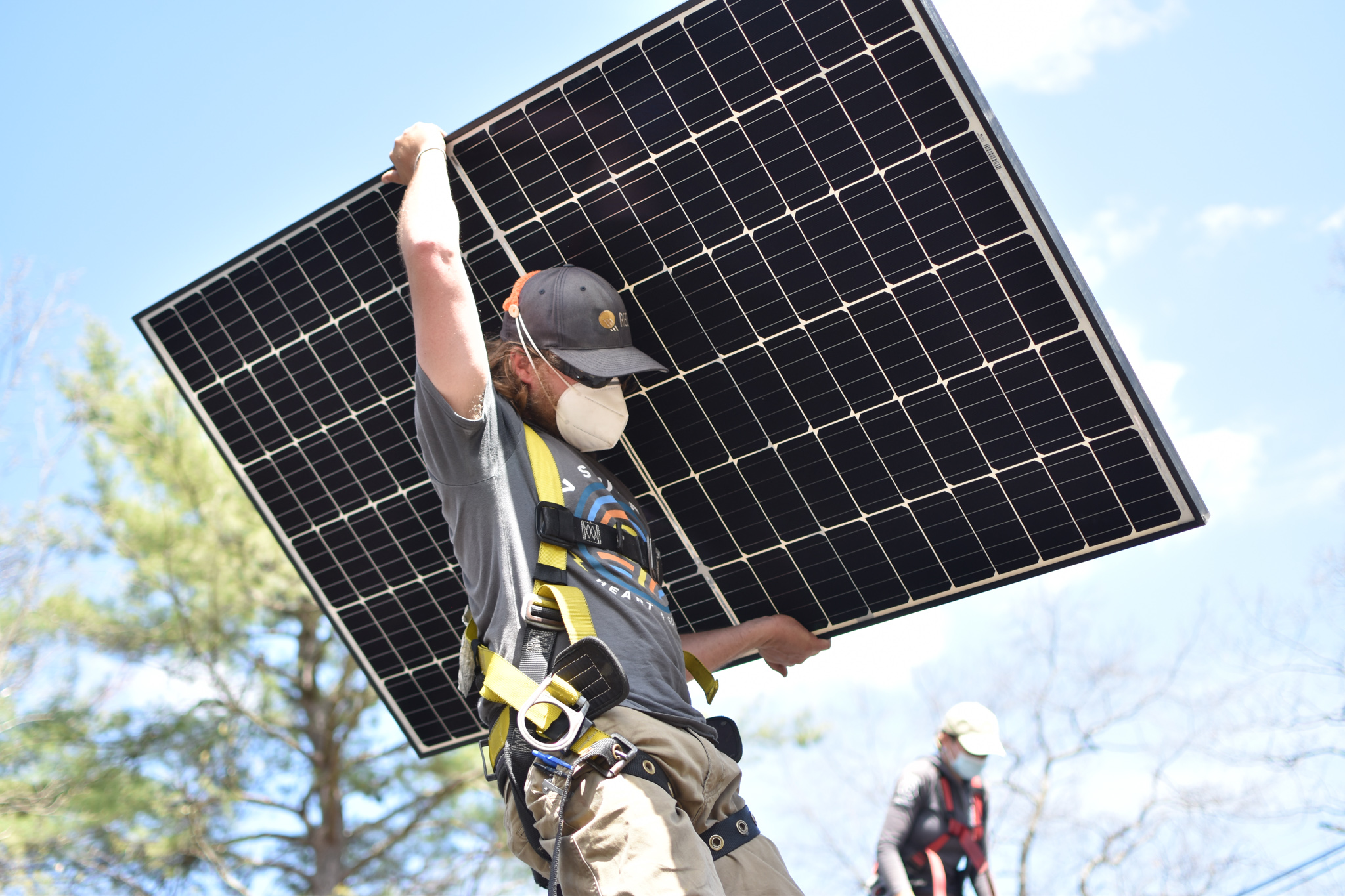 pv squared coop employee carrying solar panel