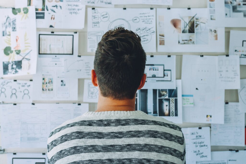 thinking man looking at documents and images on a board