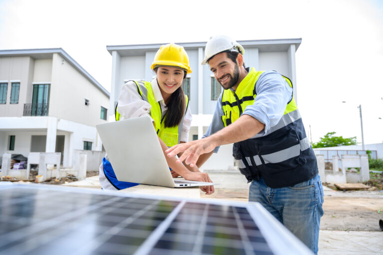 residential solar technician safety vest looking at solar software on laptop