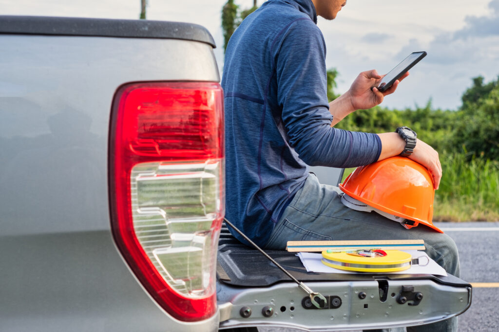 field worker on phone with solar crm software in truck bed with hard hat