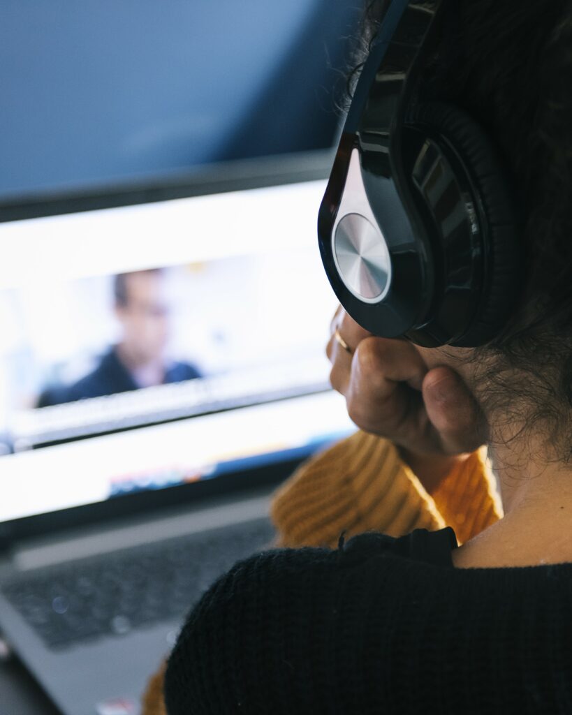 woman with headphones watching video tutorial on laptop portrait