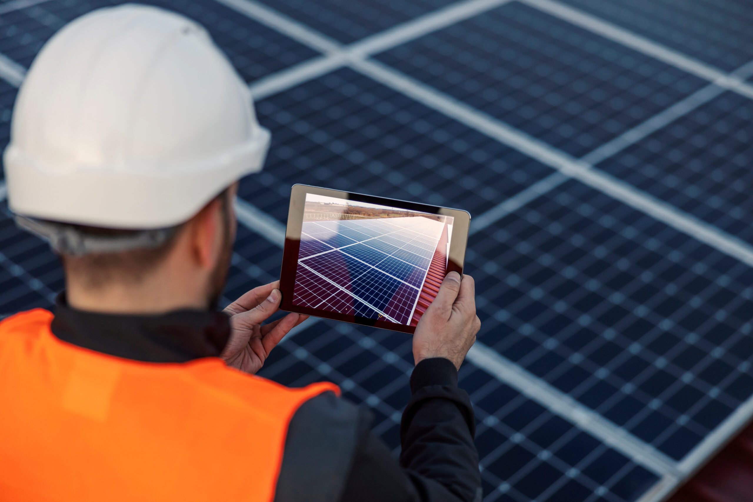 Rear view of worker taking pictures of solar panel on the roof.