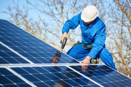 male technician solar panel installation on roof